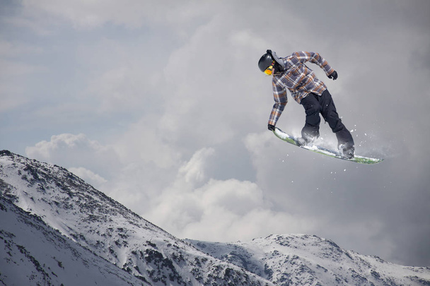 Καβαλάρης snowboard πηδάει στα βουνά. Extreme snowboard ελεύθερο άθλημα. - Φωτογραφία, εικόνα