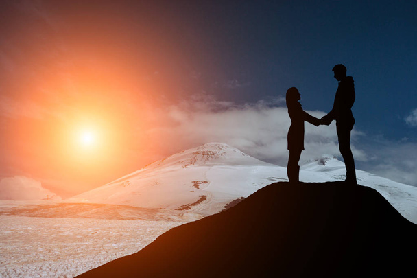 silhouet jongen en meisje op een mooie zonsondergang hand in hand - Foto, afbeelding