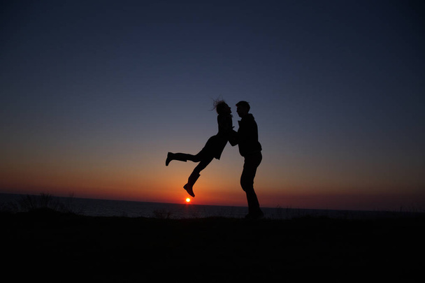 silueta chlap a dívka na krásném západu slunce držení za ruce - Fotografie, Obrázek