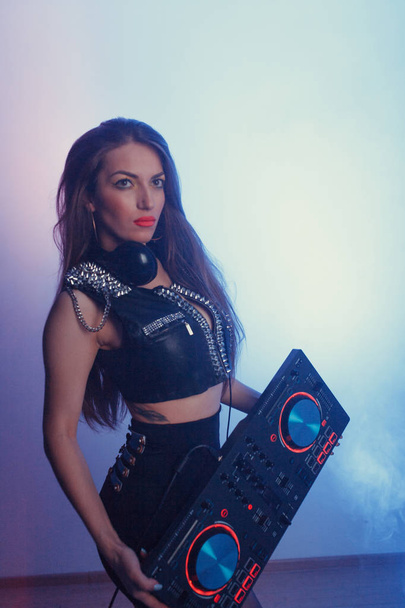 Young beautiful girl DJ with headphones holding a DJ mixer - Фото, зображення