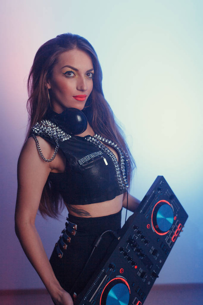 Young beautiful girl DJ in headphones holding a DJ deck - Foto, imagen