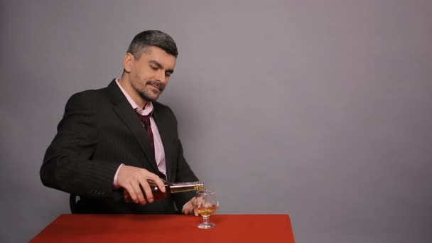 Attractive man in black suit sitting at cafe and tasting expensive cognac, joy - Imágenes, Vídeo