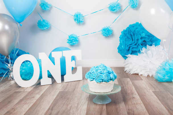 Décoration de fond festive pour la célébration de l'anniversaire avec gâteau gastronomique, lettres disant un et ballons bleus en studio, gâteau smash concept première année
 - Photo, image