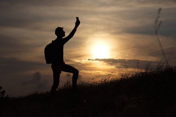 mężczyzna stojący na wzgórzu patrząc link na tle pięknego zachodu słońca - Zdjęcie, obraz