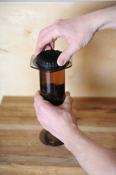 Objetos para la elaboración de café alternativo sobre un fondo de madera.. café especial. Las manos giran filtro negro
 - Foto, Imagen