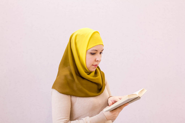 Красивая мусульманка читает книгу с хиджабом. привлекательная арабская студентка, читающая книгу
 - Фото, изображение