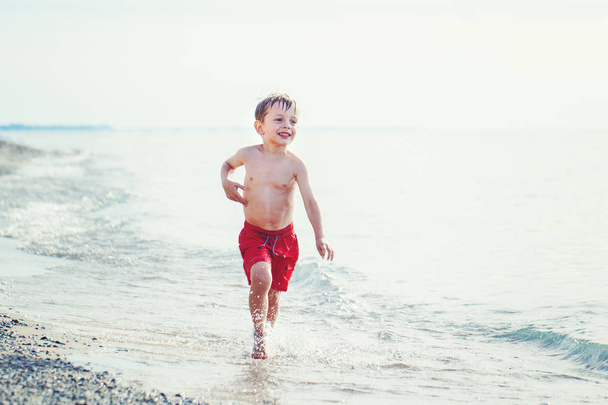 αγόρι στο κόκκινο κολύμπι σορτς τρέξιμο  - Φωτογραφία, εικόνα