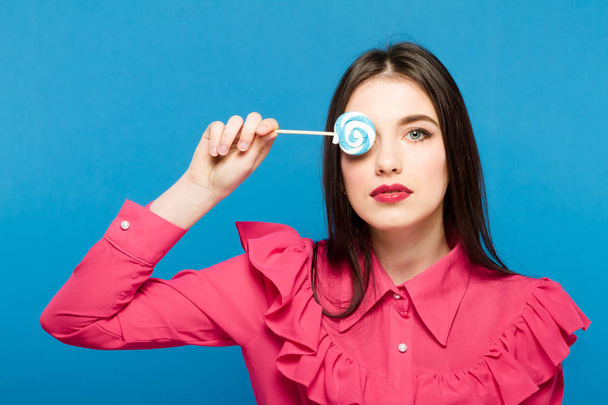 Beautiful woman close up with a lollypop, high-quality beauty on blue background - Foto, Bild