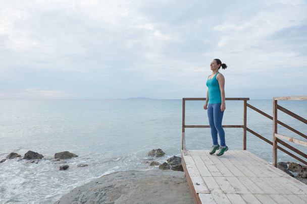 Jeune femme debout sur un pont en bois au bord de la mer
 - Photo, image