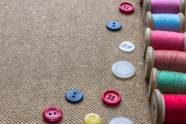 herramientas de costura (muchos hilos de colores diferentes, muchos botones diferentes) sobre fondo de madera
 - Foto, imagen