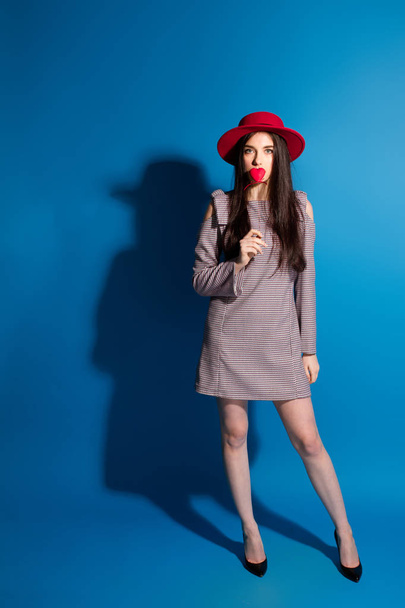 Fashion portrait pretty sweet young woman with red lips making air kiss with lollipop heart wearing hat - Φωτογραφία, εικόνα