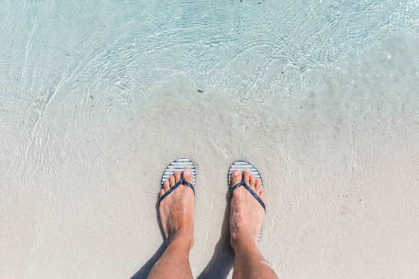 Male feet wearing female flip flops at beach - Fotografie, Obrázek