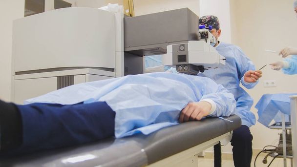 der Patient liegt auf dem Operationstisch während der augenärztlichen Operation ohne Betäubung - Laser-Sehkorrektur - Foto, Bild