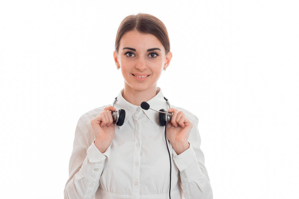 beautiful young girl smiling stands up straight and keeps the headphones on your neck - Foto, Imagen