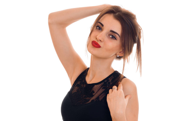 Portrait of an attractive young woman in a black dress and red lipstick that keeps hair and looks into the camera - Foto, Bild