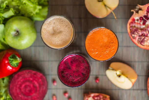 three glasses of different fresh juice. Beet, carrot and apple juices on grey wood background - Photo, Image