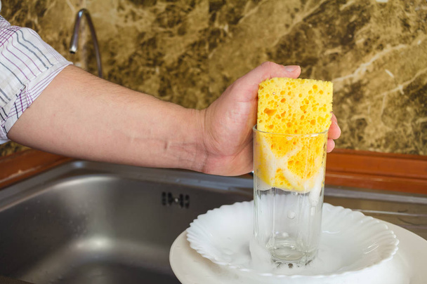 Manos de hombre, lavando una esponja con espuma los platos de la cocina
 - Foto, imagen