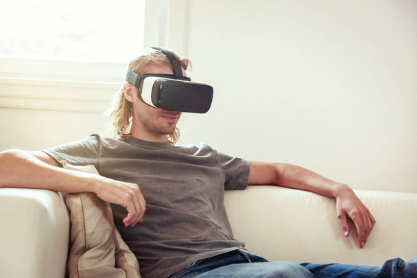 Young Man Sitting On Couch, Using Vr Glasses - 写真・画像