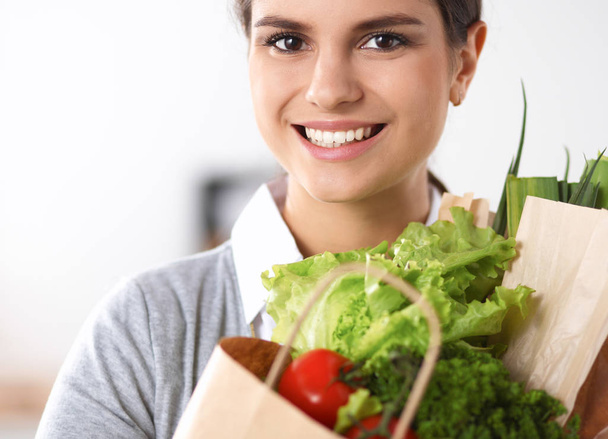 Young woman holding grocery shopping bag with vegetables Standing in the kitchen. - 写真・画像