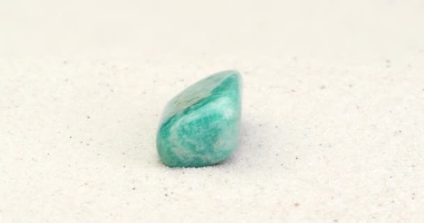 Pedra preciosa amazonita girando na areia branca
 - Filmagem, Vídeo