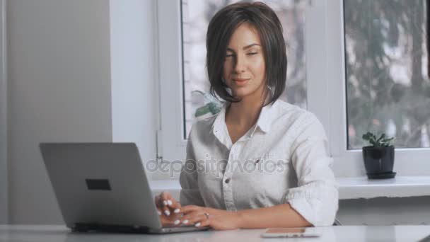 attractive business woman in a white shirt works at a laptop in the office - Filmati, video