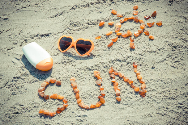 Vintage photo, Word and shape of sun, sunglasses with sun lotion on sand at beach, summer time - 写真・画像