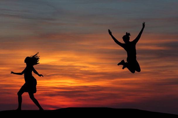 Two beautiful silhouette of a girl jumping at sunset - Fotoğraf, Görsel