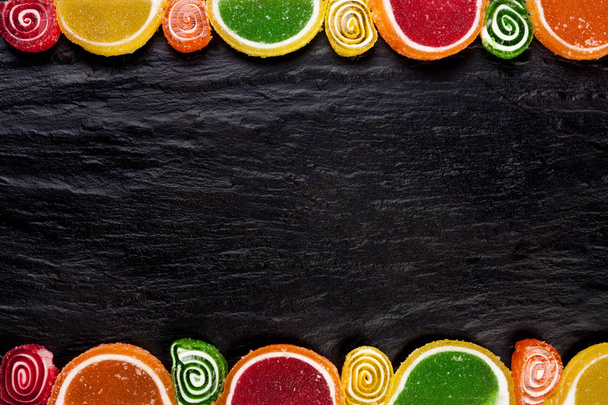 Frame from fruit jellies on a dark background. Top view with copy space - 写真・画像