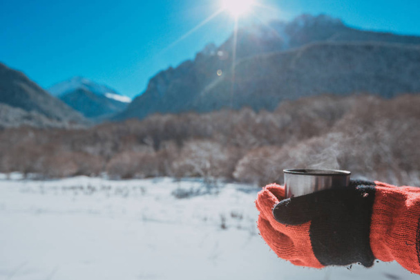 Homem segurando uma garrafa térmica em uma montanha nevada
 - Foto, Imagem