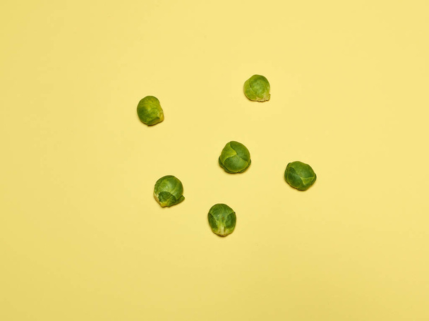 The piles of Brussels sprouts on a yellow background - Valokuva, kuva