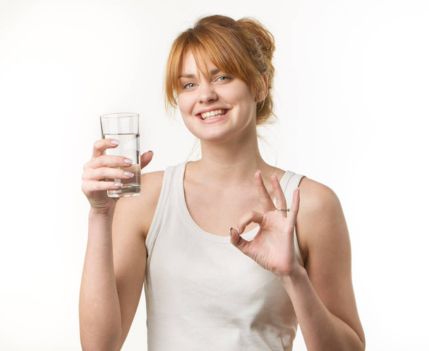 sporty woman over gray background holding glass of water - Zdjęcie, obraz