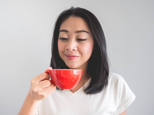 Mosoly ázsiai nő piros pohár kávét iszik. - Fotó, kép