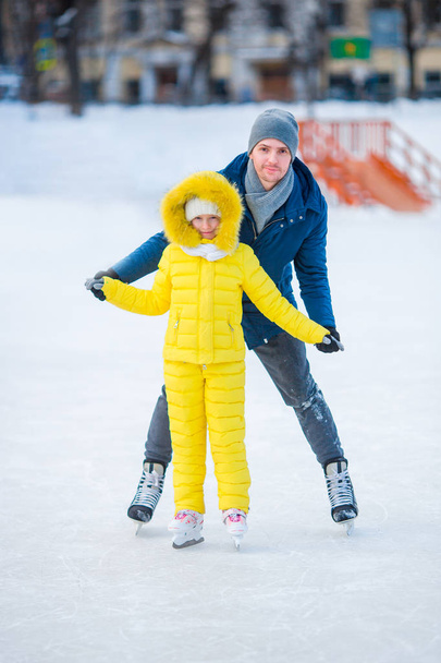 Schattig meisje met vader leren schaatsen op de ijsbaan - Foto, afbeelding