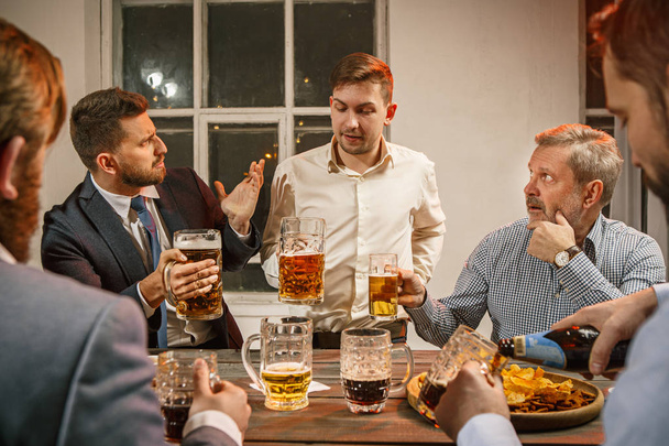 Grupo de amigos disfrutando de bebidas por la noche con cerveza
 - Foto, imagen