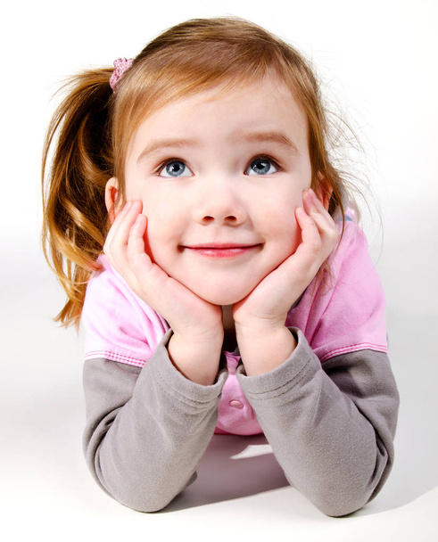 Portrait of cute smiling little girl lying on the floor - Photo, image
