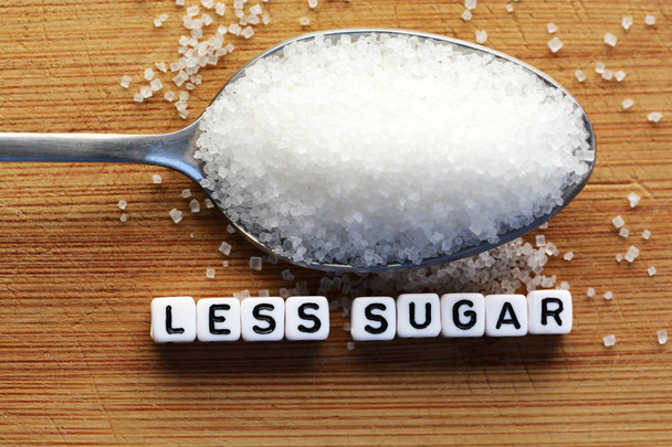 Meno testo di zucchero da blocchi di lettere piastrellate e mucchio di zucchero su un cucchiaio suggerendo concetto di dieta
 - Foto, immagini