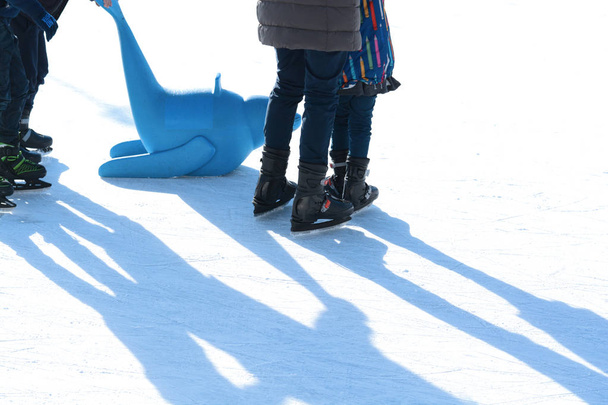Сімейні забави на відкритому ковзанах, дитина вчиться кататися на ковзанах з пластиковою пломбою як тренувальні засоби
 - Фото, зображення