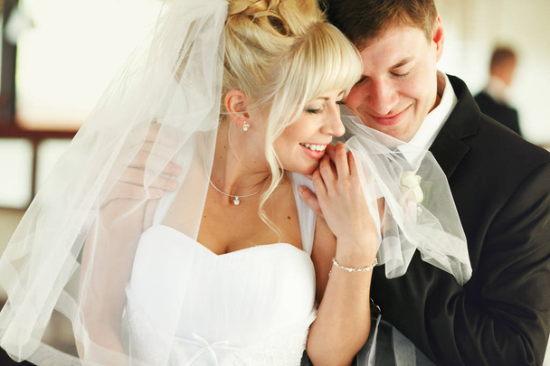 Groom holds bride's shoulder tenderly and smiles  - Φωτογραφία, εικόνα