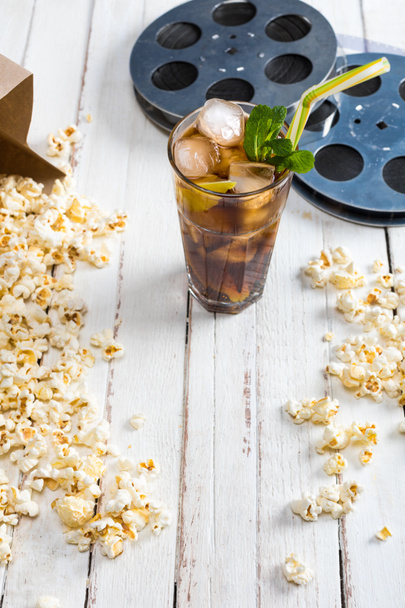 Popcorn with iced tea and film reels   - 写真・画像