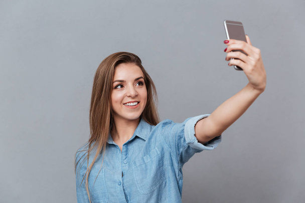 Woman in shirt making selfie on smartphone - Фото, зображення