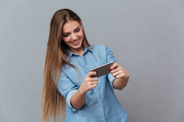 Smiling Woman in shirt playing on phone - Foto, Imagen