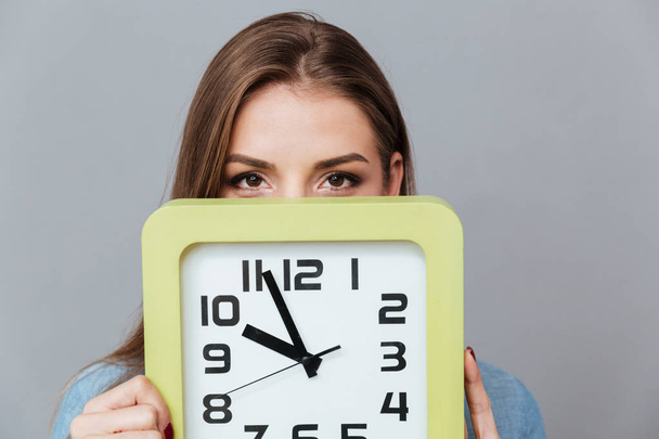 Woman in shirt hiding behind the clock - Foto, imagen