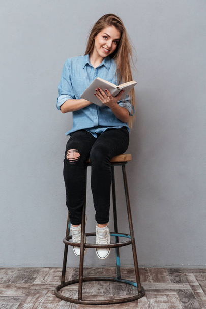 Vertical image of Woman sitting on chair and reading book - Fotó, kép