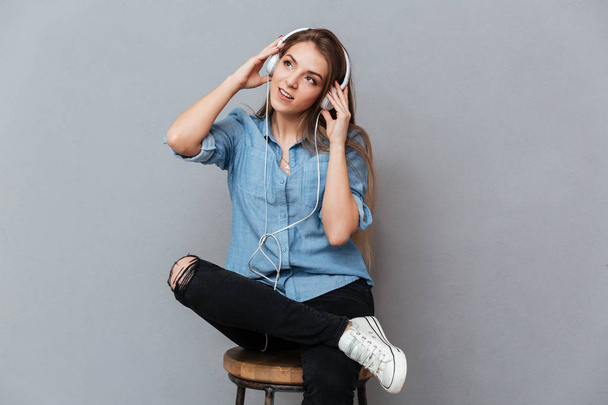 Woman in shirt sitting on chair and listening to music - Foto, Imagen
