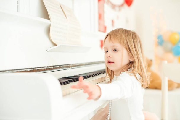 Petite fille mignonne jouant du piano dans la salle de lumière
. - Photo, image