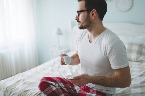 Man in pajamas enjoying coffee - Фото, изображение