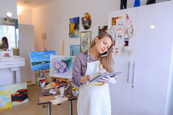 Chica artista sosteniendo el teléfono móvil y el uso, hablar, escribir pluma o
 - Foto, imagen