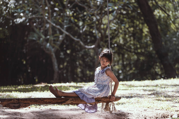 Самотня дівчина сидить на гойдалці в парку
. - Фото, зображення