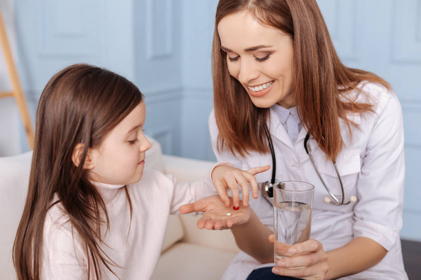 Cheerful doctor giving pills to little girl - Foto, Imagen