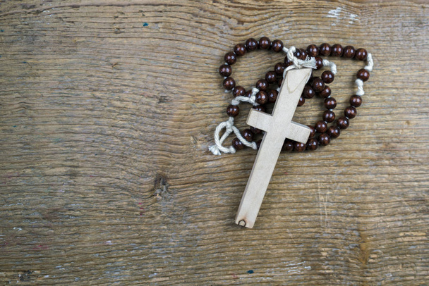 Simple rosario católico y cruz sobre madera rústica
 - Foto, imagen